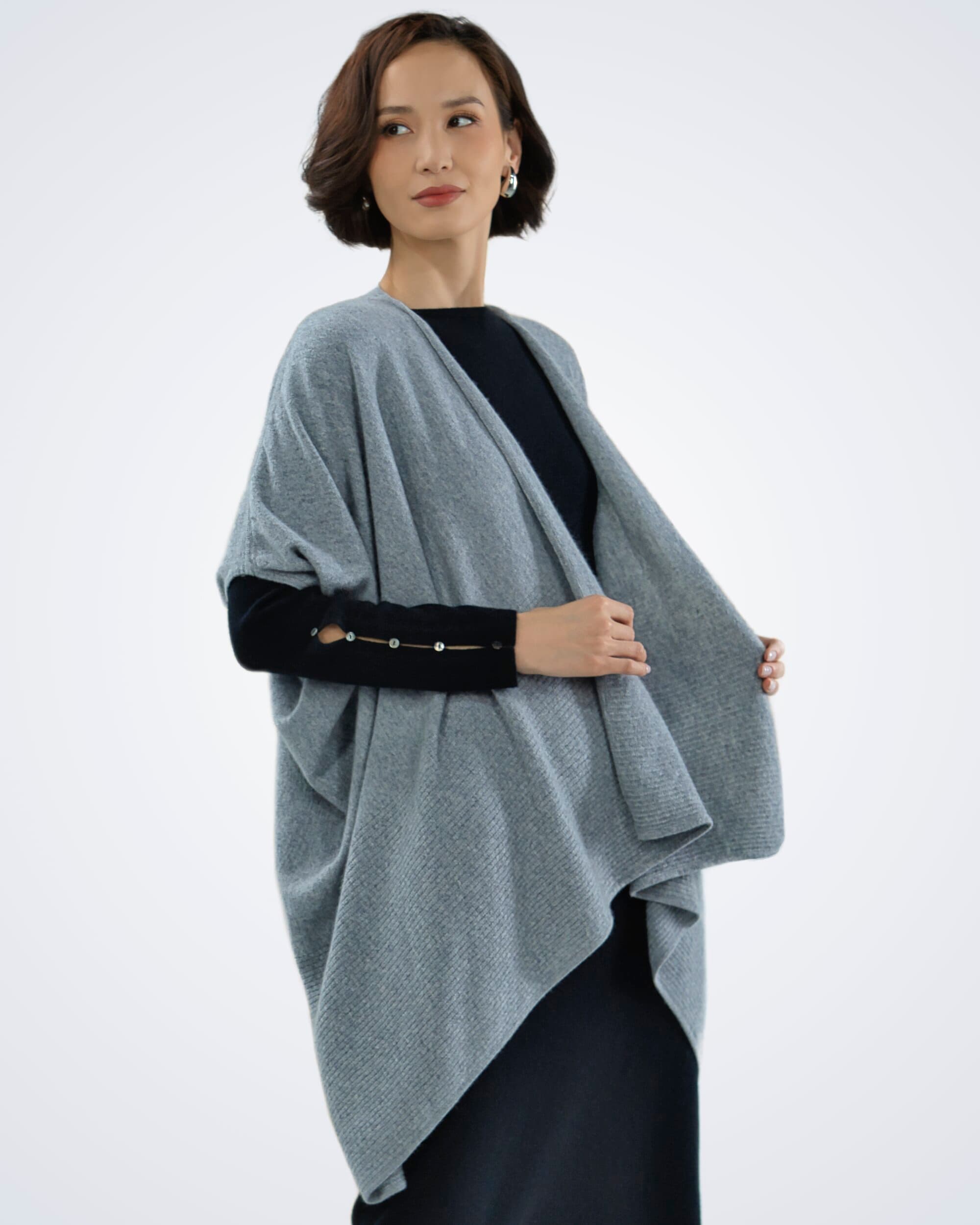 Model outdoors wearing a mint green batwing turtleneck cashmere poncho with ribbing